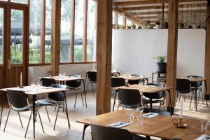 un restaurante con mesas y sillas de madera y ventanas en De 6 Linden Boutique Hotel, en Sluis