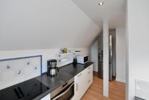 a kitchen with white cabinets and a black counter top at Lille Solskin in Tönning