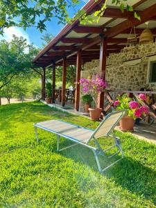 a patio with a bench and a table in the grass at Ktima Panagias in Ormos Panagias