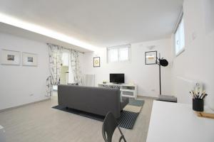 een witte woonkamer met een bank en een tv bij Christina's Home in Desenzano del Garda