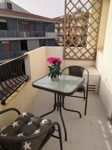 una mesa y sillas en un balcón con un jarrón de flores en A casa di Nanè, en Marina di Ragusa