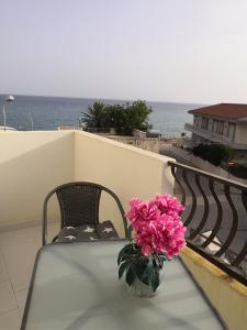 una mesa con un jarrón de flores rosas en el balcón en A casa di Nanè, en Marina di Ragusa