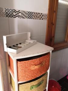 un armario blanco con cestas en el baño en A casa di Nanè, en Marina di Ragusa