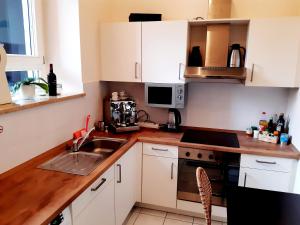 eine Küche mit weißen Schränken, einer Spüle und einer Mikrowelle in der Unterkunft Tillyhome in Nürnberg