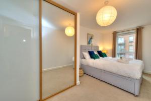 a bedroom with a large mirror in front of a bed at Executive Oakgrove Apartment by PAY AS U STAY in Milton Keynes