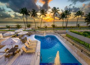 a pool with chairs and umbrellas and the ocean at Hardman Praia Hotel in João Pessoa