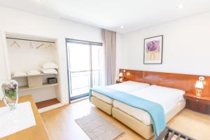 Un dormitorio con una cama y una ventana grande. en Apartamento Mar & Sol, en Póvoa de Varzim