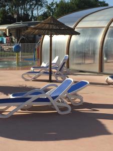 a row of lounge chairs and an umbrella in a playground at ALINOA in Ouistreham