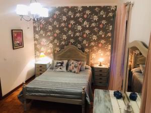 1 dormitorio con 1 cama y una pared con flores en Casa de Katiolo, en Figueira de Castelo Rodrigo