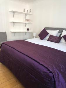 a bedroom with a large bed with purple sheets at ACE Largs Ground Floor Apartment with Garden in Largs