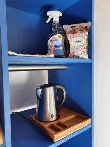 ハノーファーにあるSmart Hostel by Landgasthof Velber 24h7dの木製のトレイの上にティーケトルが置かれた青い棚