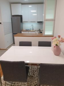 une cuisine avec une table, des chaises et un vase de fleurs dans l'établissement Apartman 33 FREE PRIVATE GARAGE, à Novi Sad