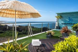 eine Terrasse mit einem Tisch, einem Sonnenschirm und dem Meer in der Unterkunft Apartamentos Turísticos La Boutique del Mar in Conil de la Frontera