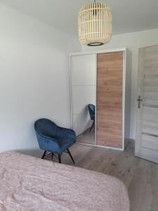 a bedroom with a blue chair and a mirror at Apartament Nova in Dębina