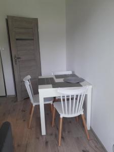 un escritorio blanco con 2 sillas blancas y una mesa en Apartament Nova, en Debina