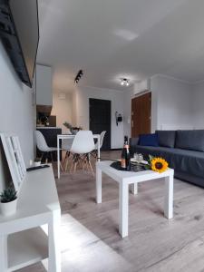 een woonkamer met een witte tafel en een blauwe bank bij River House - Apartament z ogródkiem in Szczecin