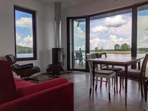 een woonkamer met een tafel, stoelen en ramen bij Dom na Wodzie in Kruklanki