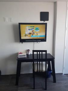 einen Tisch mit einem Stuhl und einen TV an der Wand in der Unterkunft Thiers Appt in Mexiko-Stadt