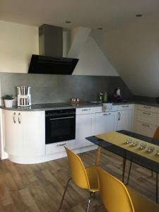 a kitchen with white cabinets and a table with yellow chairs at Gästehaus Lüßvitz in Ummanz