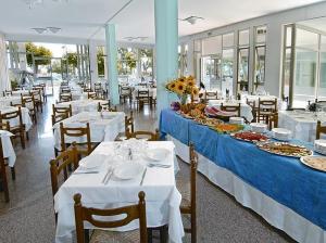 restauracja z białymi stołami i krzesłami z jedzeniem w obiekcie Hotel Miramare w mieście Giulianova