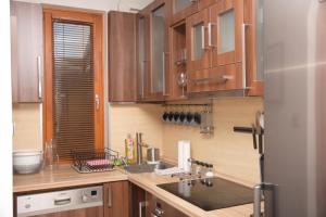 a kitchen with wooden cabinets and a sink and a refrigerator at A-Boutique Apartman Gyula in Gyula