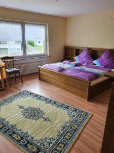 Schlafzimmer mit einem Bett mit lila Kissen und einem Teppich in der Unterkunft Ferienhaus Naturblick in Berndorf