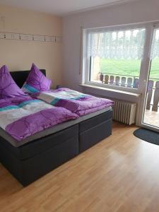 Un dormitorio con una cama con sábanas moradas y una ventana en Ferienhaus-Naturblick, en Berndorf