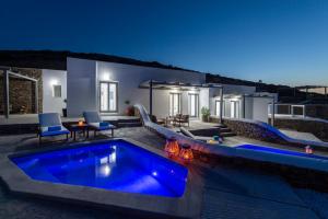 a villa with a swimming pool at night at Peters Place - Paros Resort in Parasporos