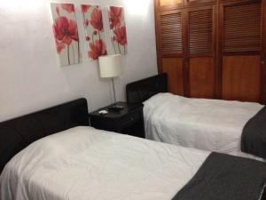 um quarto de hotel com duas camas e uma mesa com um candeeiro em La Casa de Taty em Valledupar