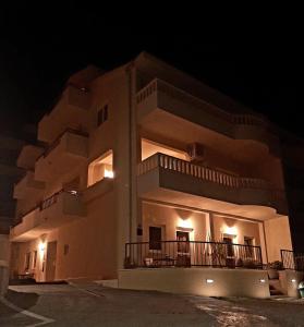 a large white building with a balcony at night at Apartments Akmadzic in Makarska