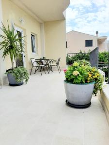 a patio with two large potted plants and tables at Apartments Akmadzic in Makarska