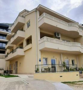 un gran edificio de apartamentos con balcones y mesas en Apartments Akmadzic, en Makarska