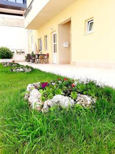 a flower bed in the grass in front of a house at Apartments Akmadzic in Makarska