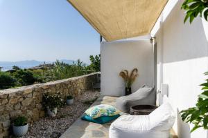 a patio with white walls and pillows and a stone wall at Live & Dream in Vrisi/ Mykonos
