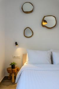 een slaapkamer met een wit bed en 2 spiegels aan de muur bij Live & Dream in Vrisi/ Mykonos