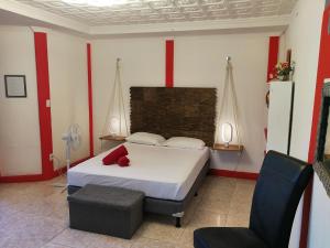 ein Schlafzimmer mit einem weißen Bett und einem Stuhl in der Unterkunft Secret Garden in Cahuita