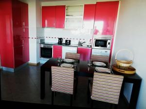 uma cozinha com armários vermelhos e uma mesa e cadeiras pretas em APARTAMENTO VISTA MAR 715 Edificio Oceano Atlantico Apartamentos Turisticos em Portimão