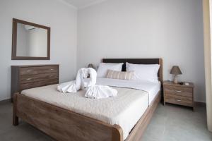 a bedroom with a bed with white sheets and a mirror at Fotini Apartments in Preveza