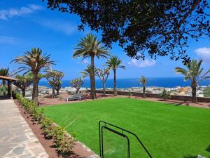 un parco con erba verde, palme e l'oceano di RK Hacienda La ReKompensa ad Arucas