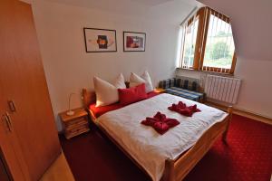 ein Schlafzimmer mit einem Bett mit roten Bögen darauf in der Unterkunft VIP Apartmany Besenova in Bešeňová