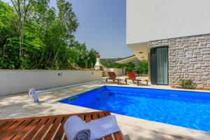 einen Pool mit zwei Stühlen und ein Haus in der Unterkunft Villa Luce in Grižane