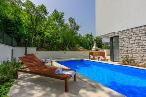 einen Pool mit einer Holzbank neben einem Haus in der Unterkunft Villa Luce in Grižane