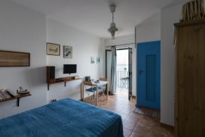 a bedroom with a blue bed and a desk with a television at Casa di Sale - Chianalea in Scilla