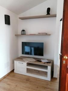 a living room with a flat screen tv on a cabinet at EFFE Apartment Golfo Aranci: Sole, Mare e Relax in Golfo Aranci