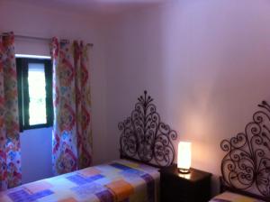 een slaapkamer met een bed, een lamp en een raam bij CASA DA AVÓ in Vila Nova de Cacela