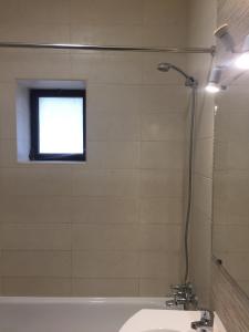 een badkamer met douche, wastafel en raam bij CASA DA AVÓ in Vila Nova de Cacela