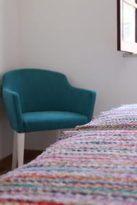 a bedroom with a bed and a blue chair at Breathe In in Zambujeira do Mar
