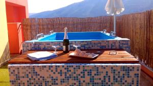 Villa Alexandros في Zóla: طاولة مع زجاجة من النبيذ بجوار حمام السباحة