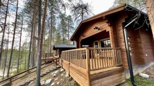 a cabin in the woods with a large deck at Lapiosalmi Wilderness Center in Posio