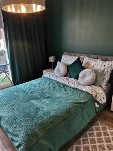 uma cama com um cobertor verde e almofadas em Apartament z widokiem na Zamek em Malbork